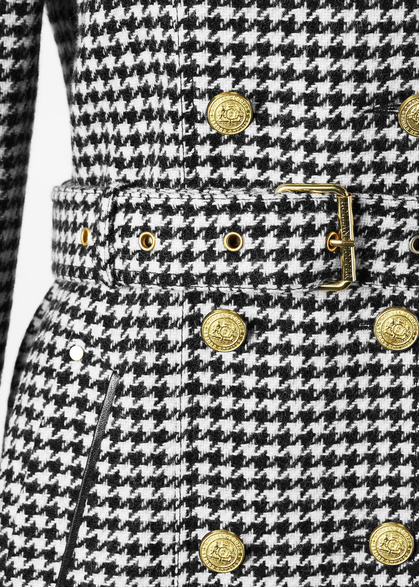 Gold button and belt detail on womens black and white houndstooth double breasted full length trench coat with black faux fur collar and cuffs
