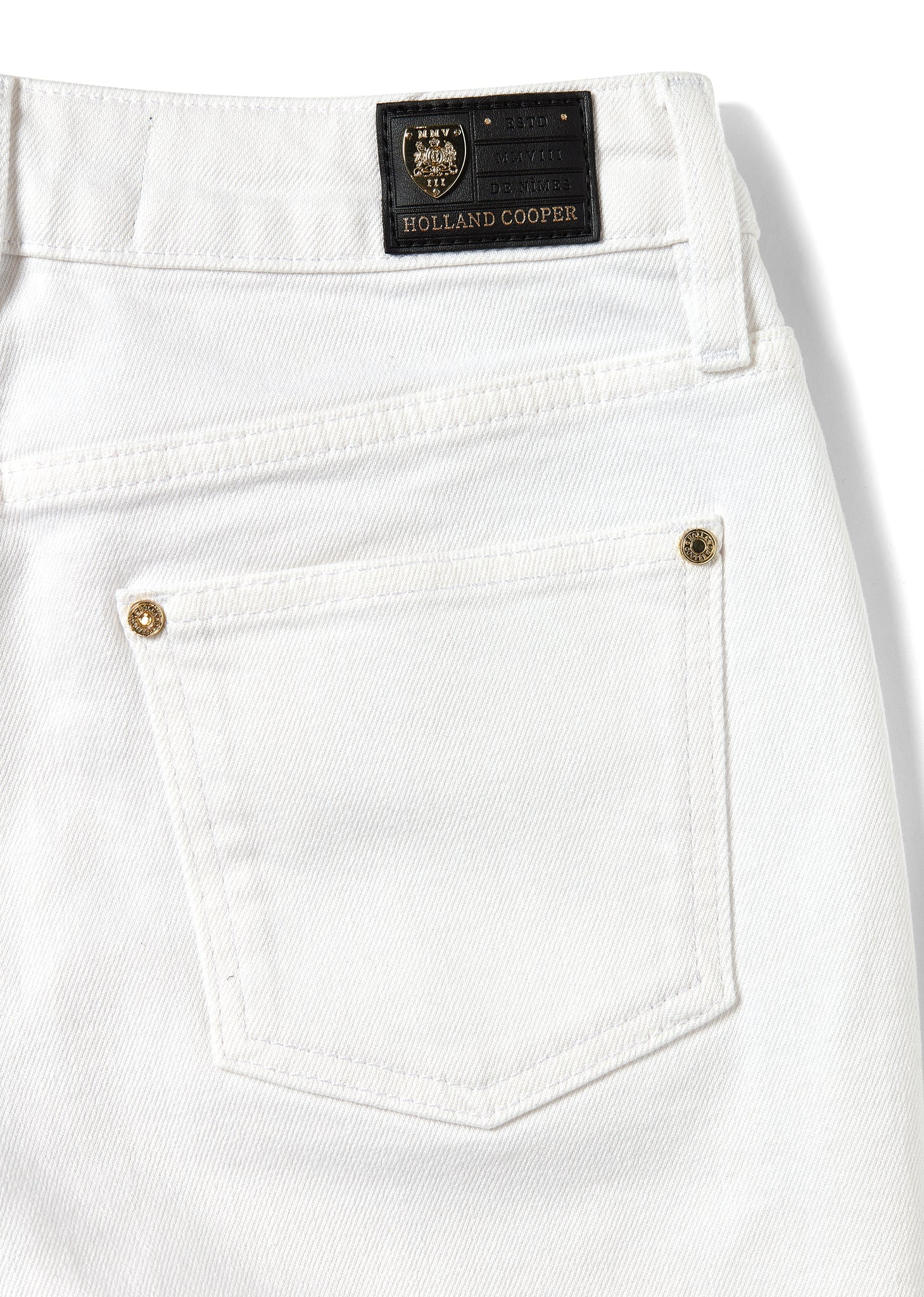 back pocket detail of womens white high waisted denim shorts with raw edge hemline and two open front pockets and two open back pockets with gold hc crest rivet in right front pocket