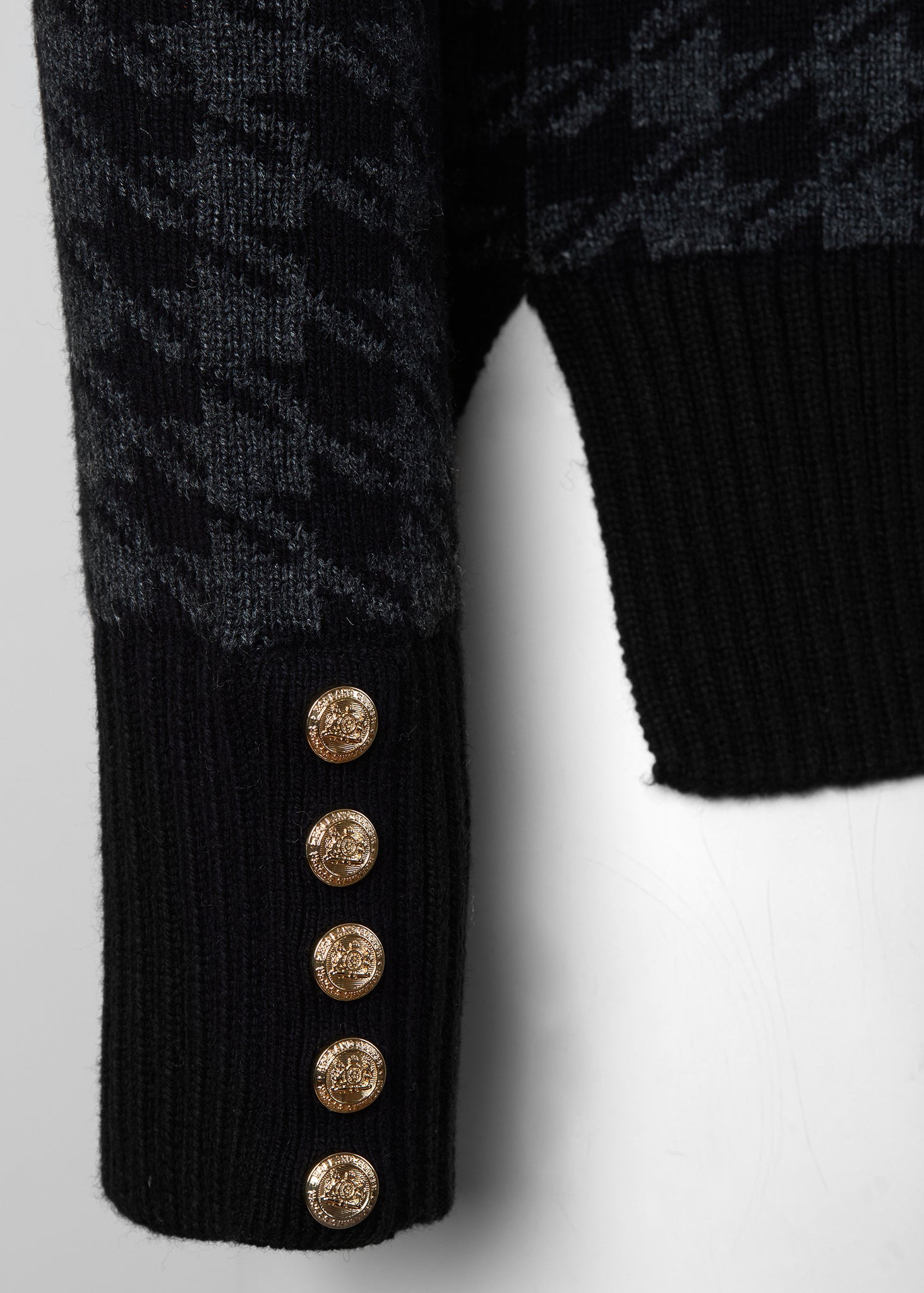 gold button detail on cuffs of a classic black and grey houndstooth jumper with contrast black cuffs, roll neck and split ribbed hem with gold button detail on the cuffs and collar