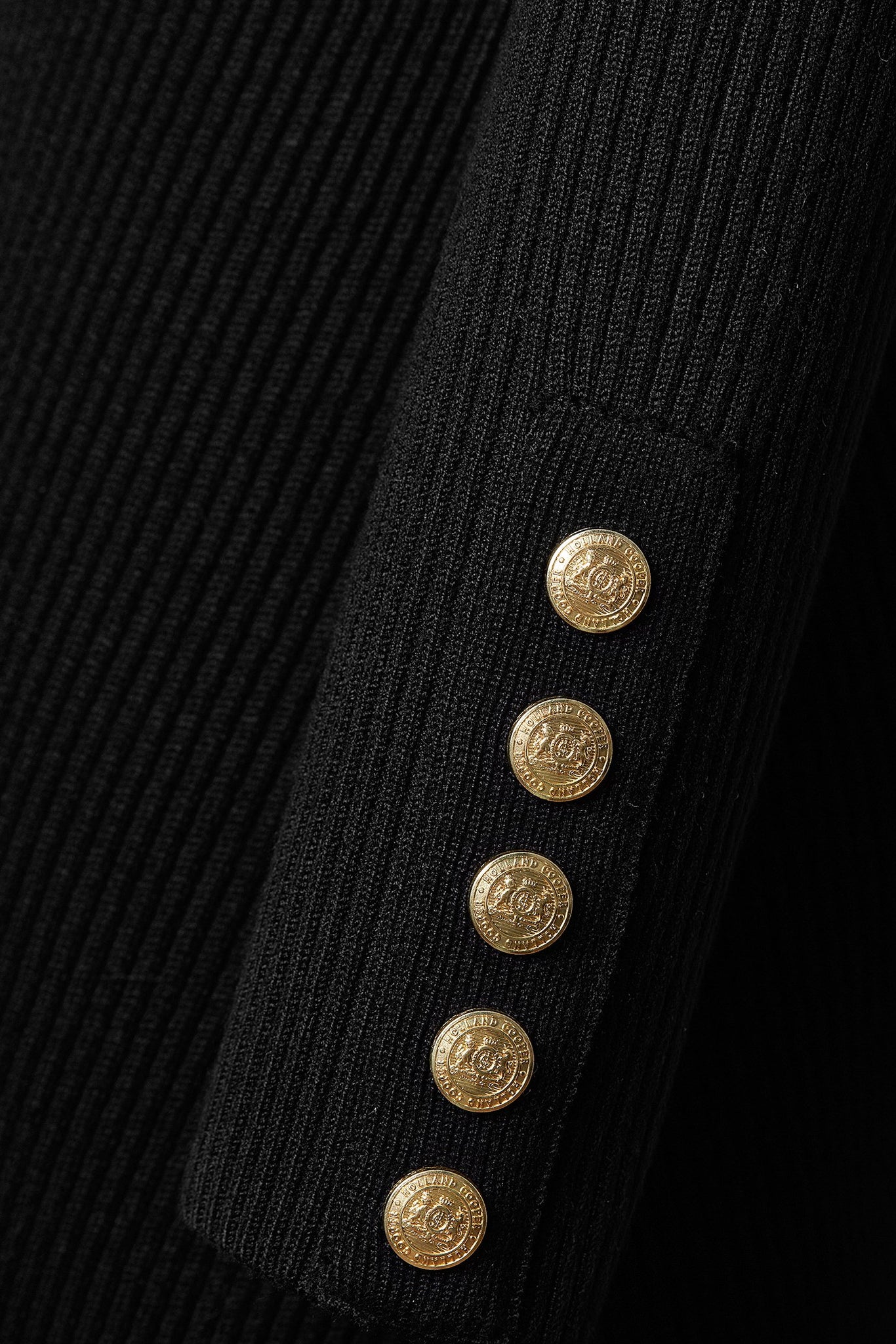detail shot of gold buttons on cuffs of womens black knitted roll neck midi dress