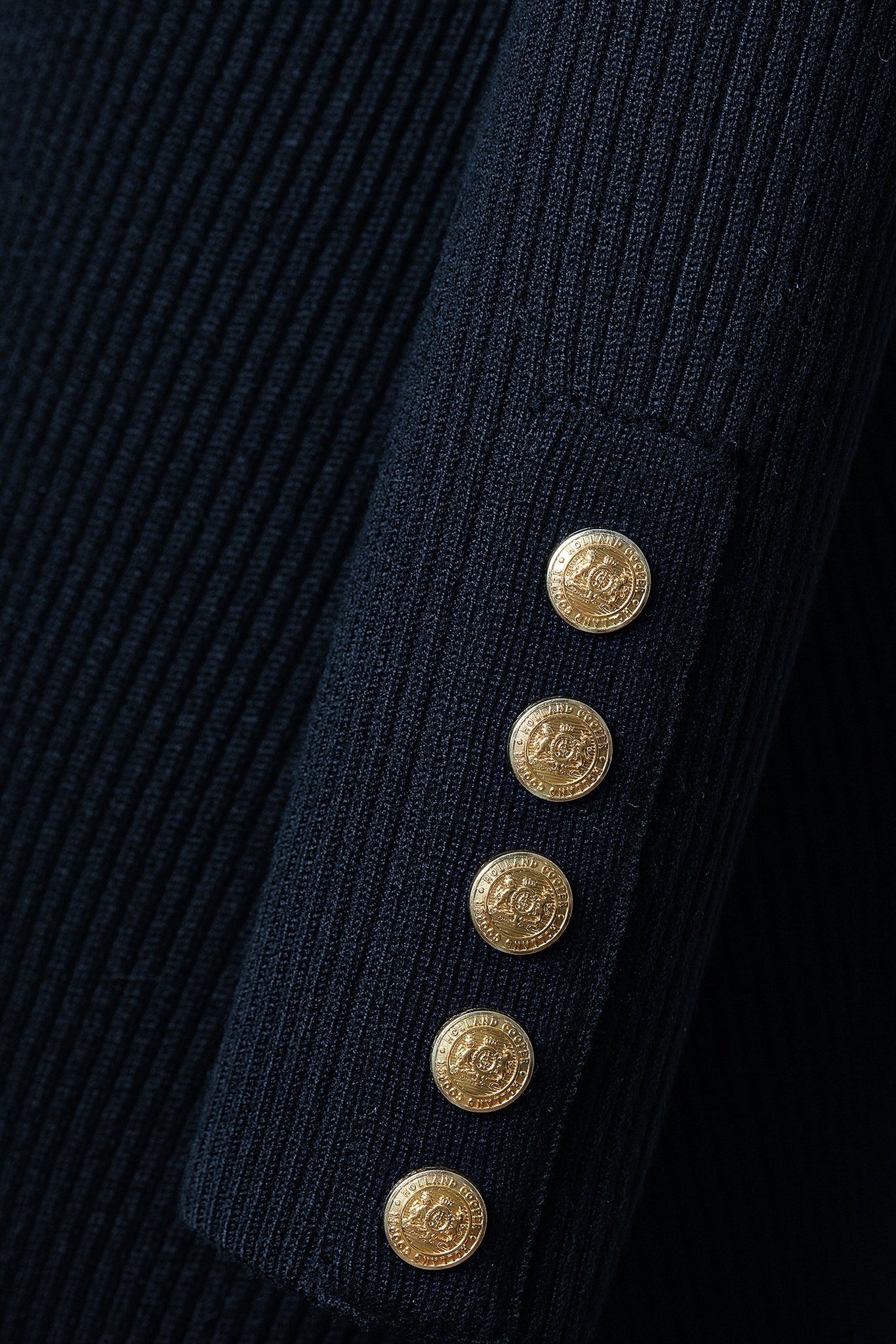 detailed shot of gold buttons on cuffs on womens navy knitted roll neck midi dress