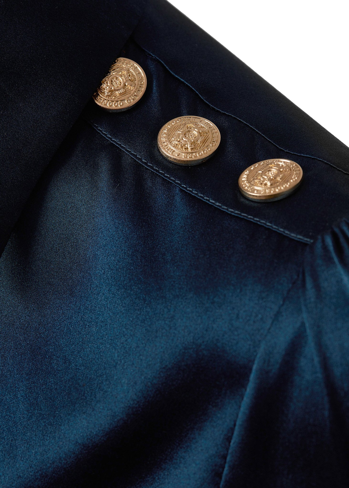 gold button shoulder detail of womens long sleeve blue silk v neck blouse with gold buttons