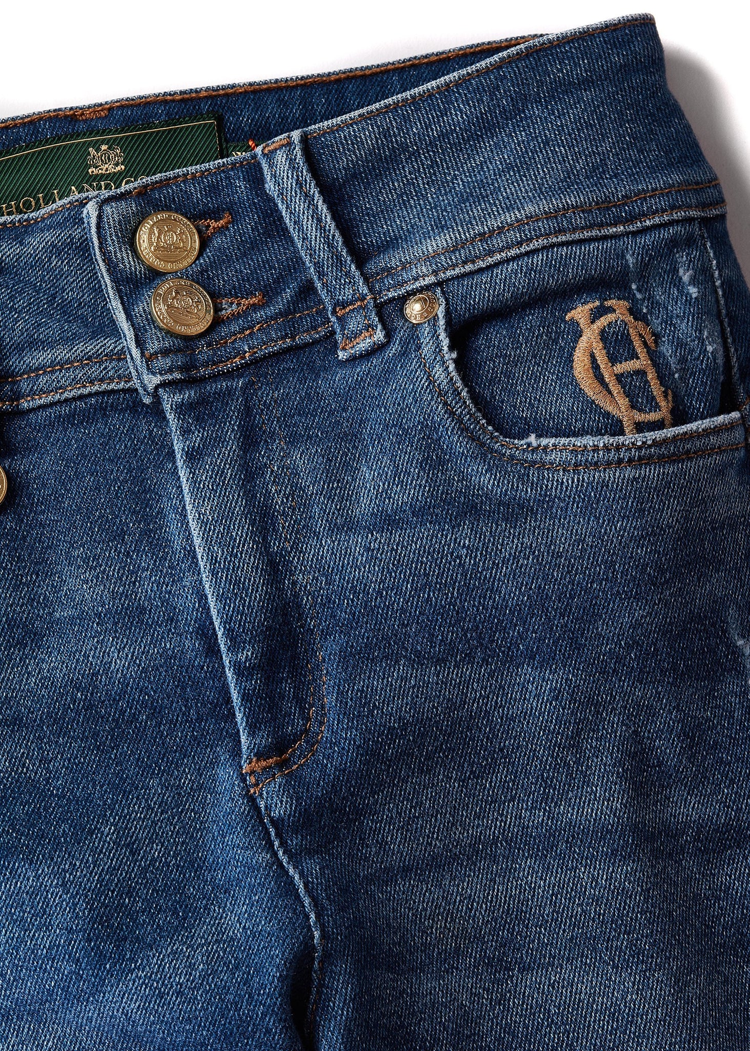 hc embroidery detail on front left pocket on womens high rise blue distressed denim skinny stretch jean with jodhpur style seams and two open pockets to the front