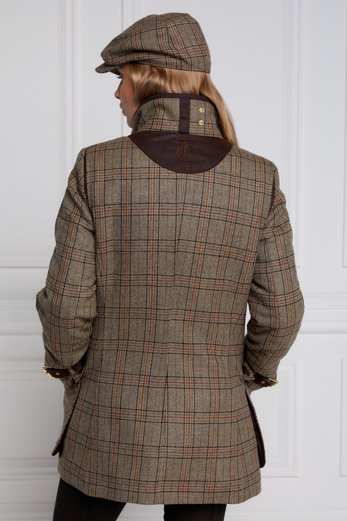 Back of woman in brown tartan tweed field coat and baker boy cap
