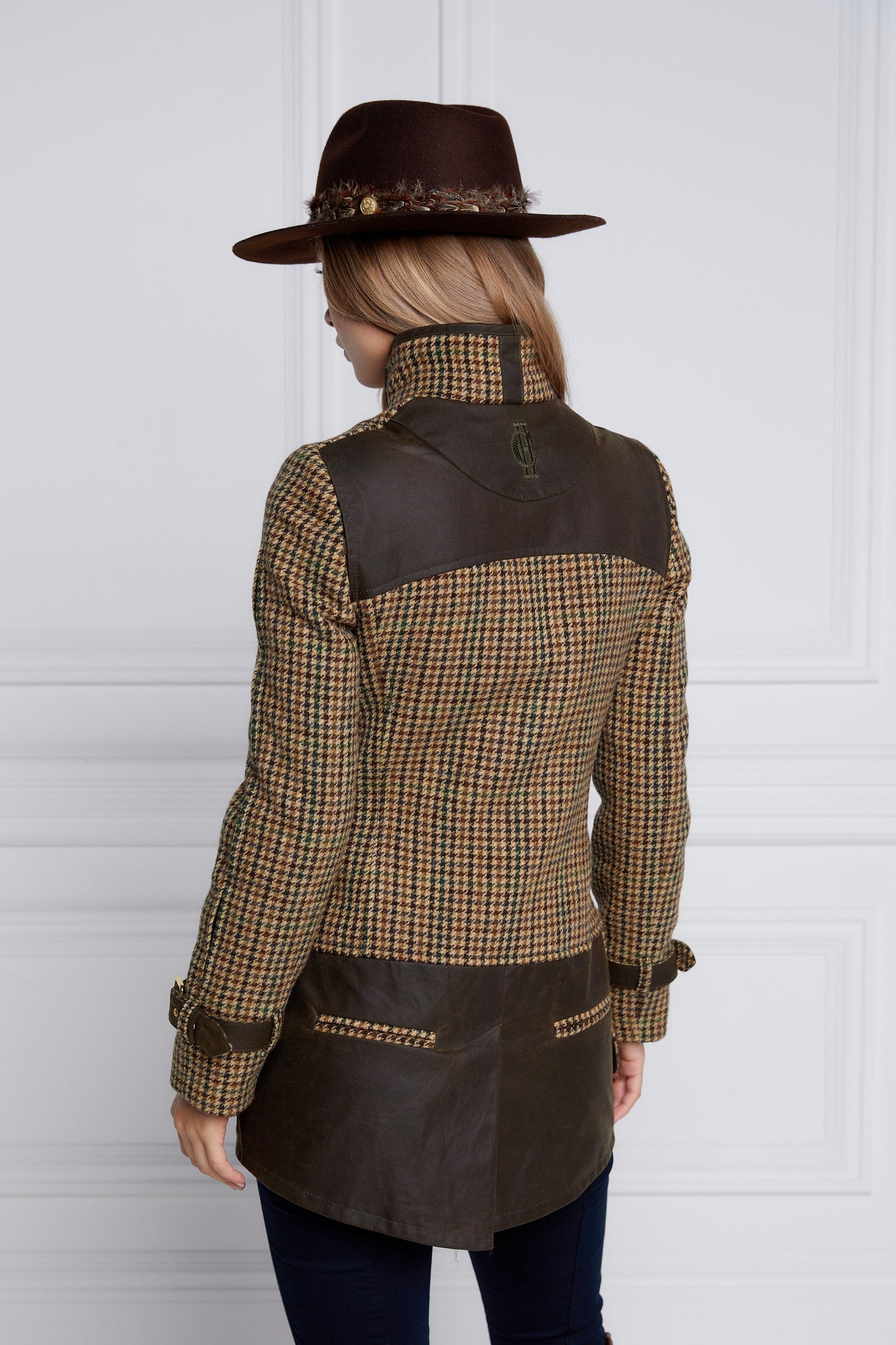 back of womens fitted field jacket in stone brown and green houndstooth tweed trimmed with contrast chocolate Millerain Wax fabric on shoulder across back and on the hip finished with horn button fastenings an buckles on the collar cuffs and hip