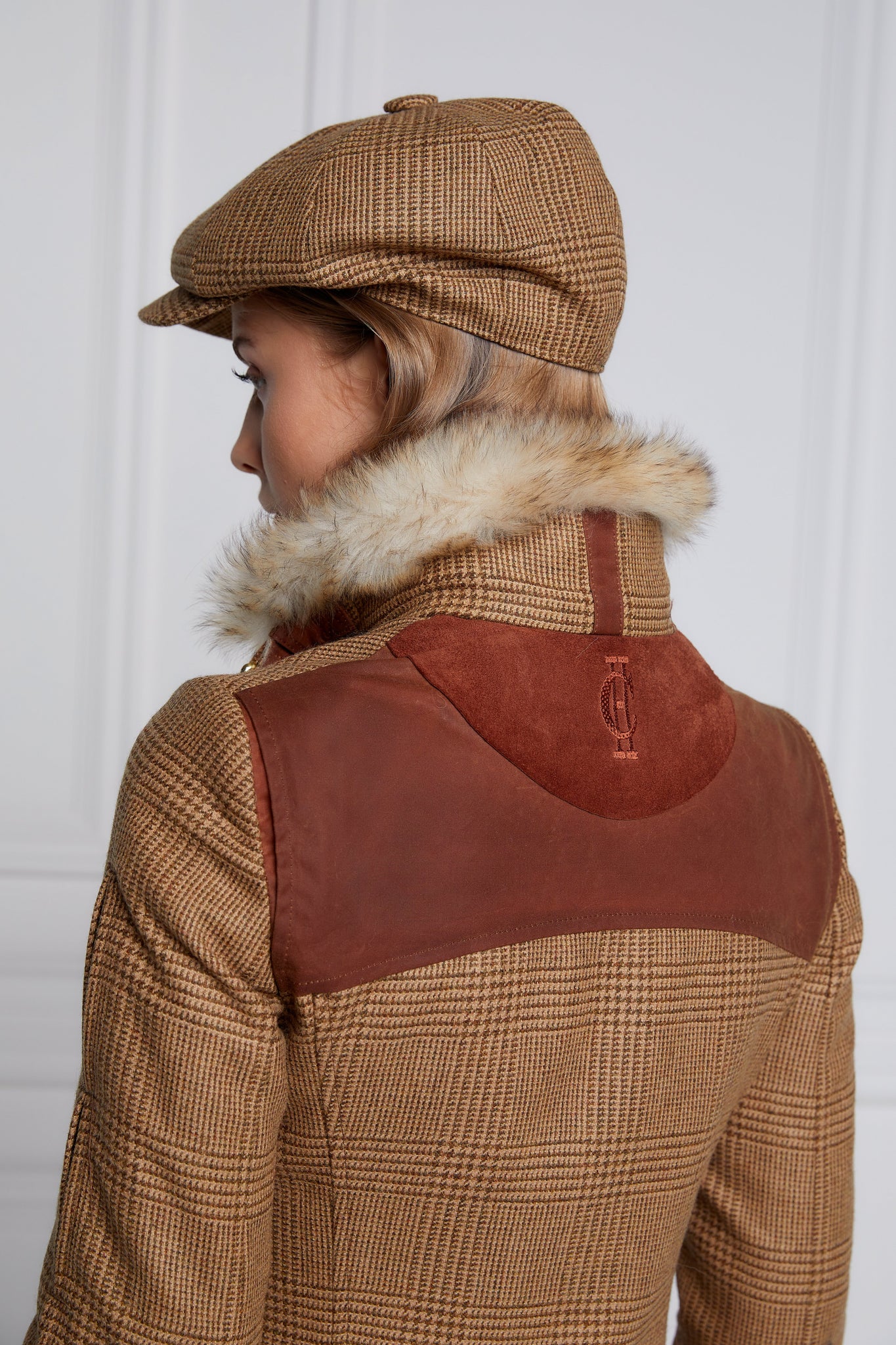 womens fitted field jacket in tawny and brown check tweed trimmed with contrast tan wax fabric on shoulder across back and on the hip with faux fur trim around the neck finished with horn button fastenings an buckles on the collar cuffs and hip