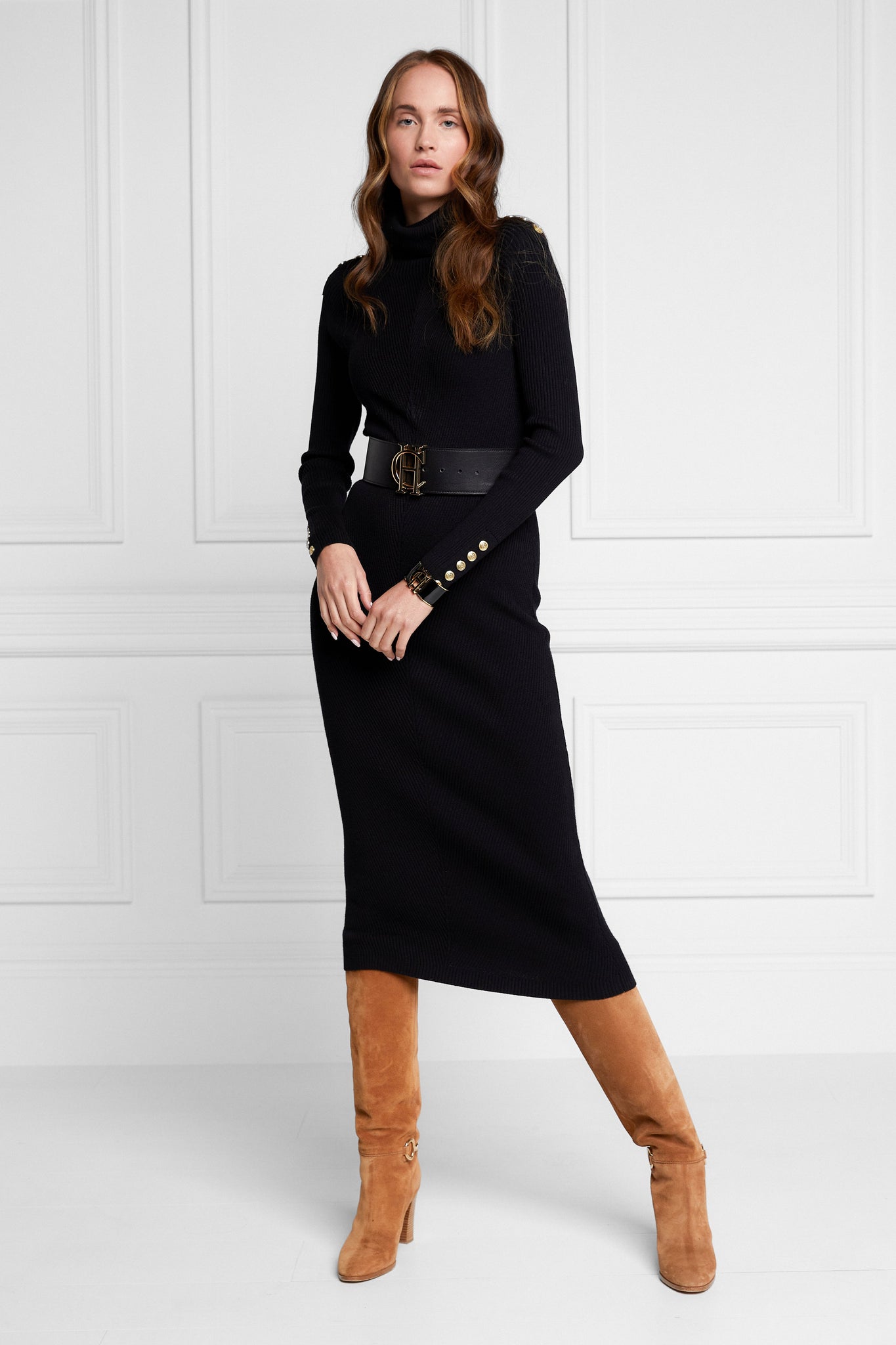 womens black knitted roll neck midi dress with gold buttons on cuffs and shoulders with black belt and tan heeled knee boots