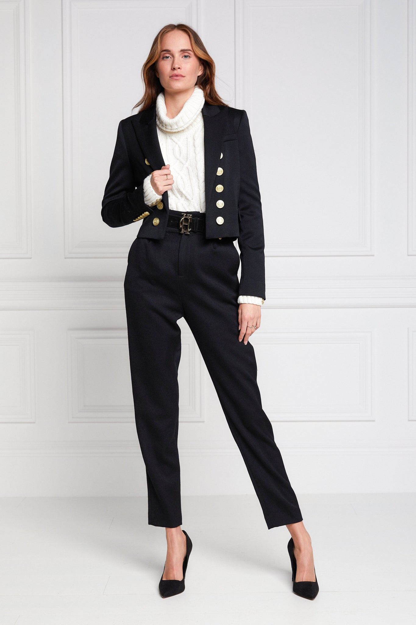 British made tailored cropped jacket in black with welt pockets and gold button detail down the front and on sleeves worn with white roll neck jumper and black tailored trousers