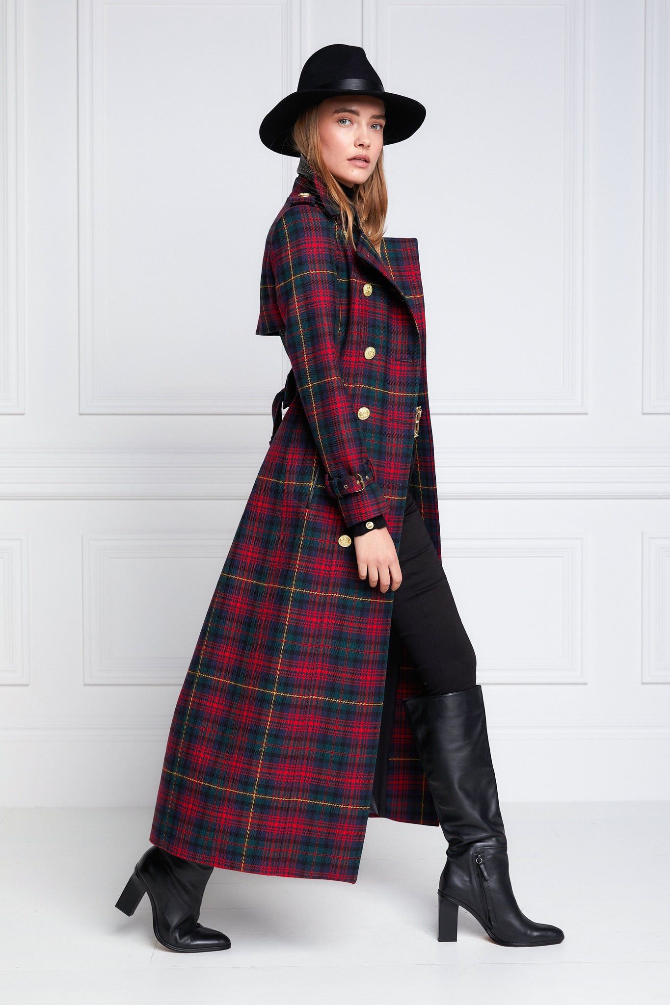 side of womens red and navy blue tartan double breasted full length wool trench coat with black trilby hat