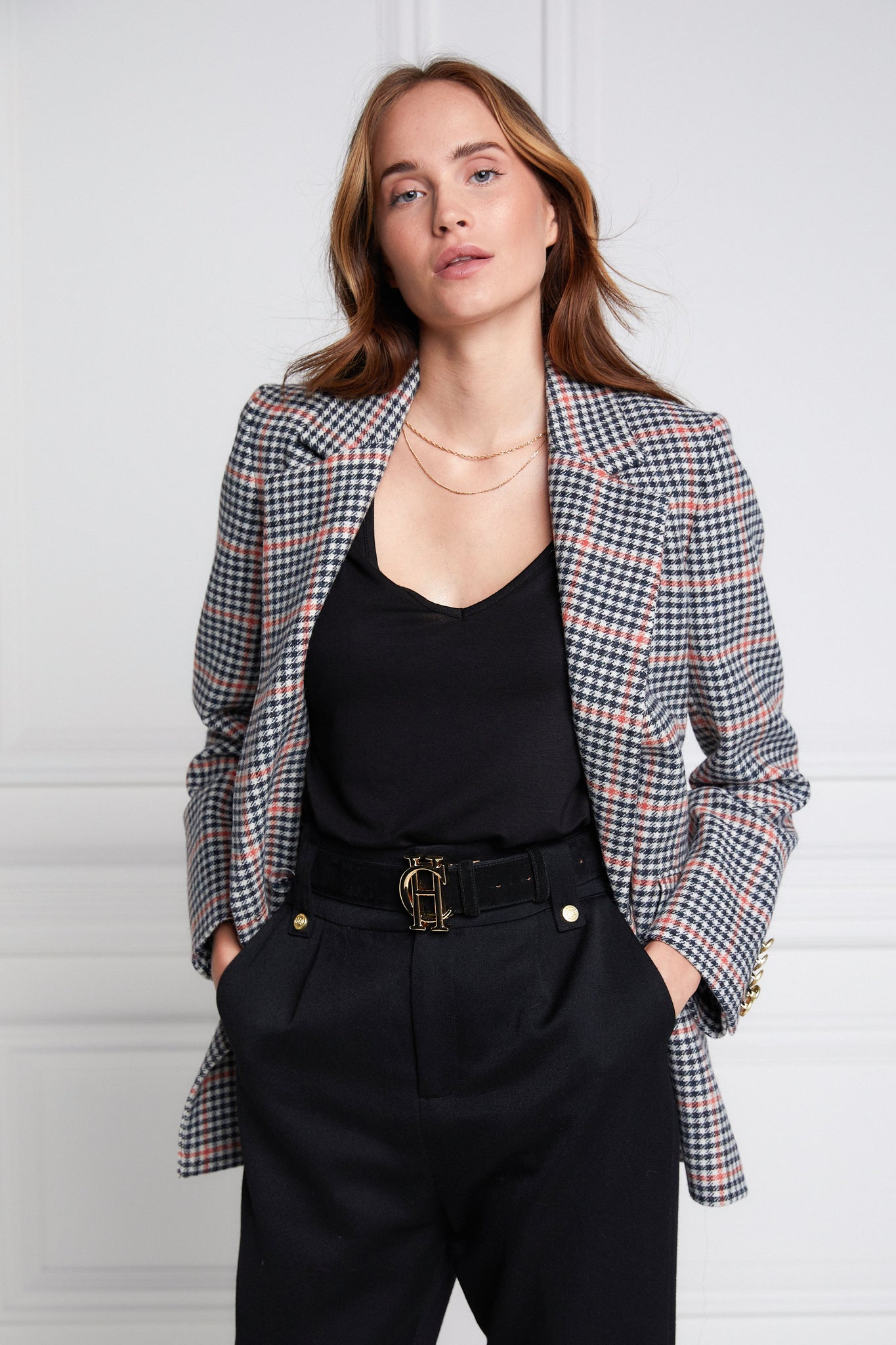 double breasted wool blazer in black white and pink check with two hip pockets and gold button details down front and on cuffs and handmade in the uk worn with black tee and black tailored trousers