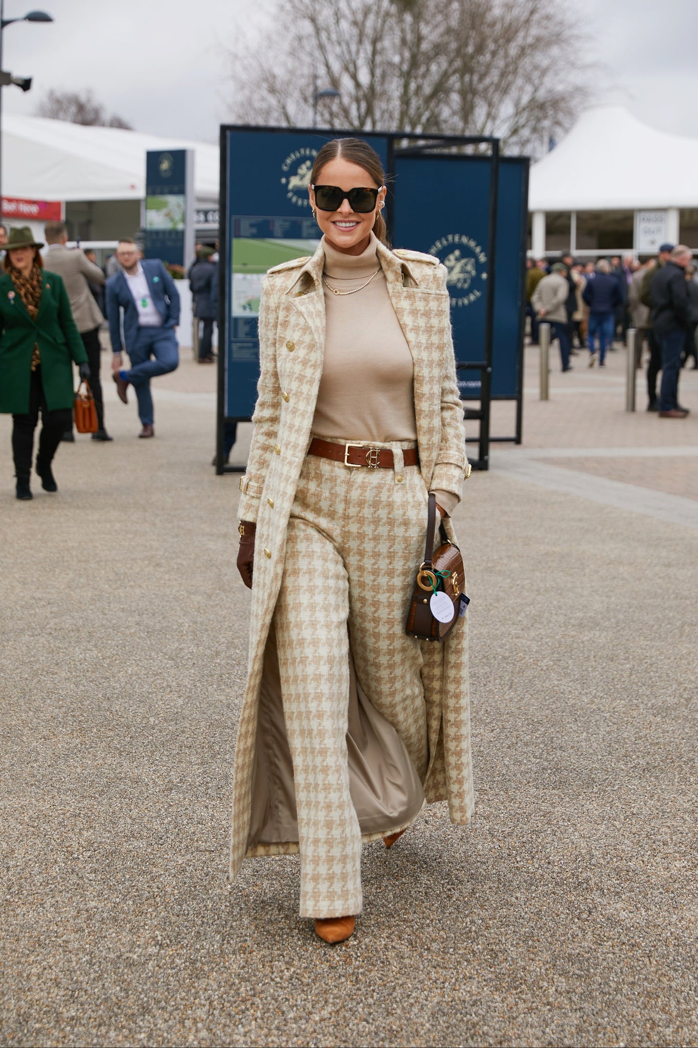 Women's camel houndstooth wool high waisted straight trousers with camel roll neck top, tan belt, camel houndstooth full length trench coat, chocolate leather gloves, black sunglasses and tan croc handbag