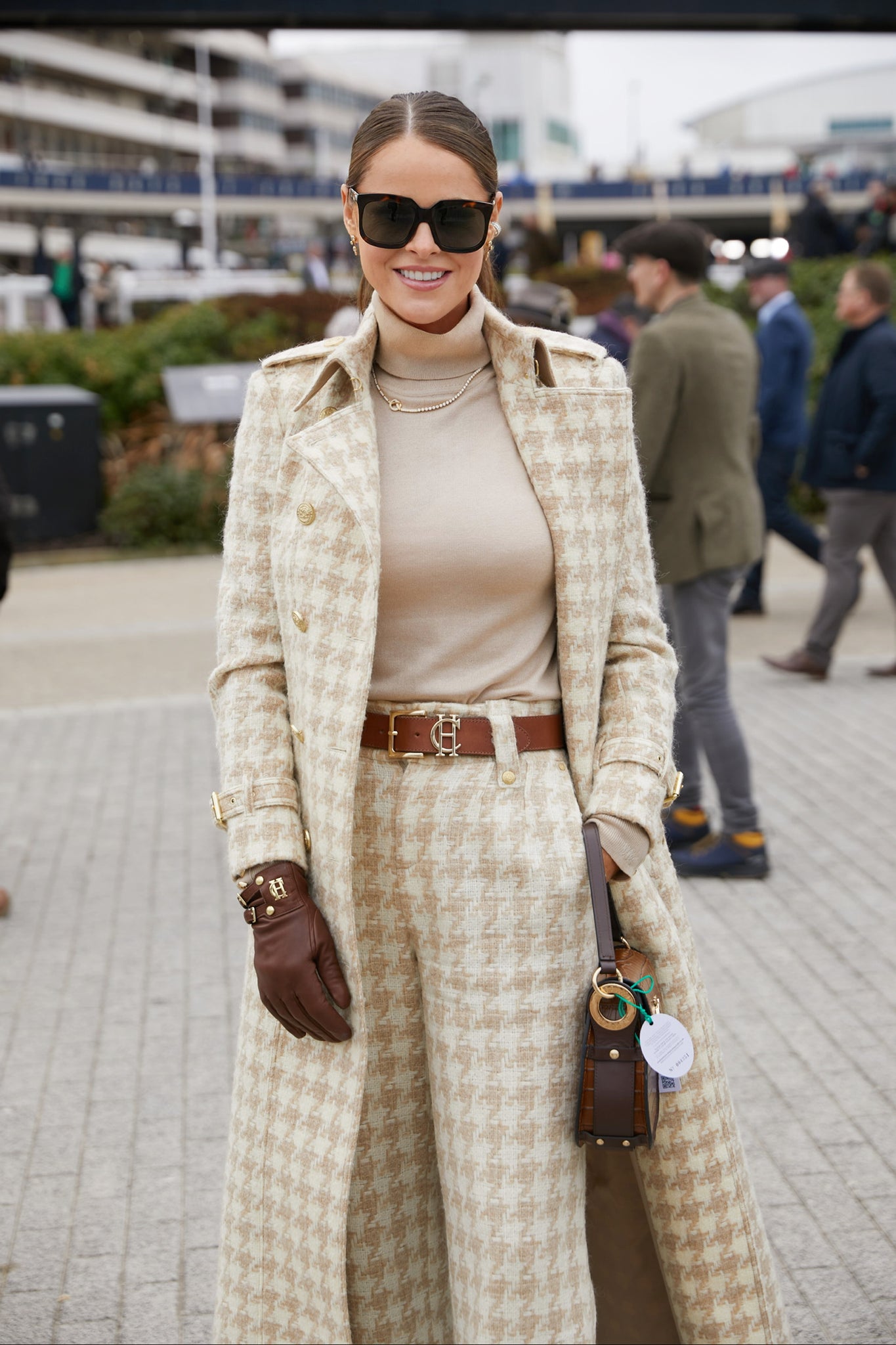 Women's camel houndstooth wool high waisted straight trousers with camel roll neck top, tan belt,  camel houndstooth full length trench coat, chocolate leather gloves, black sunglasses and tan croc handbag