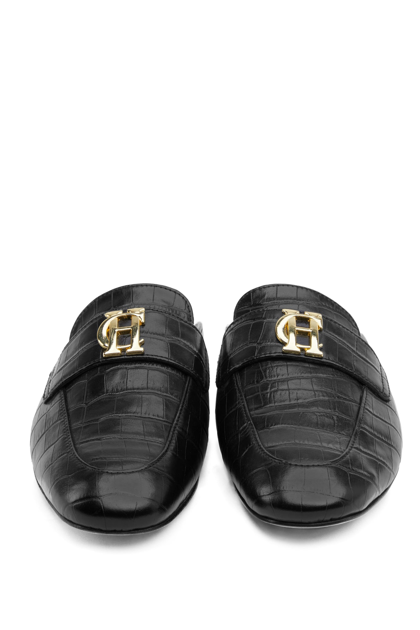 Front shot of Black croc embossed leather backless loafers with a slightly pointed toe and gold hardware to the top