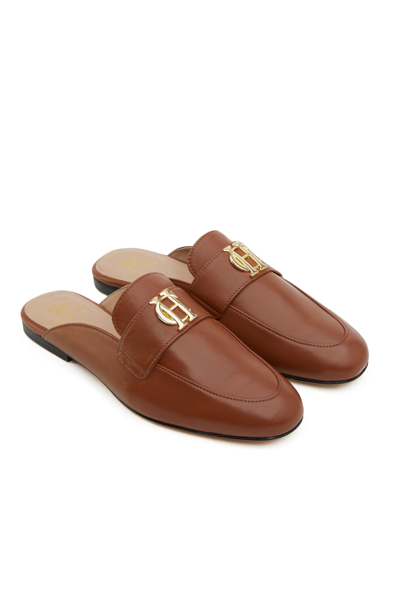 tan leather backless loafers with a slightly pointed toe and gold hardware to the top and gold foil branding to inner sole