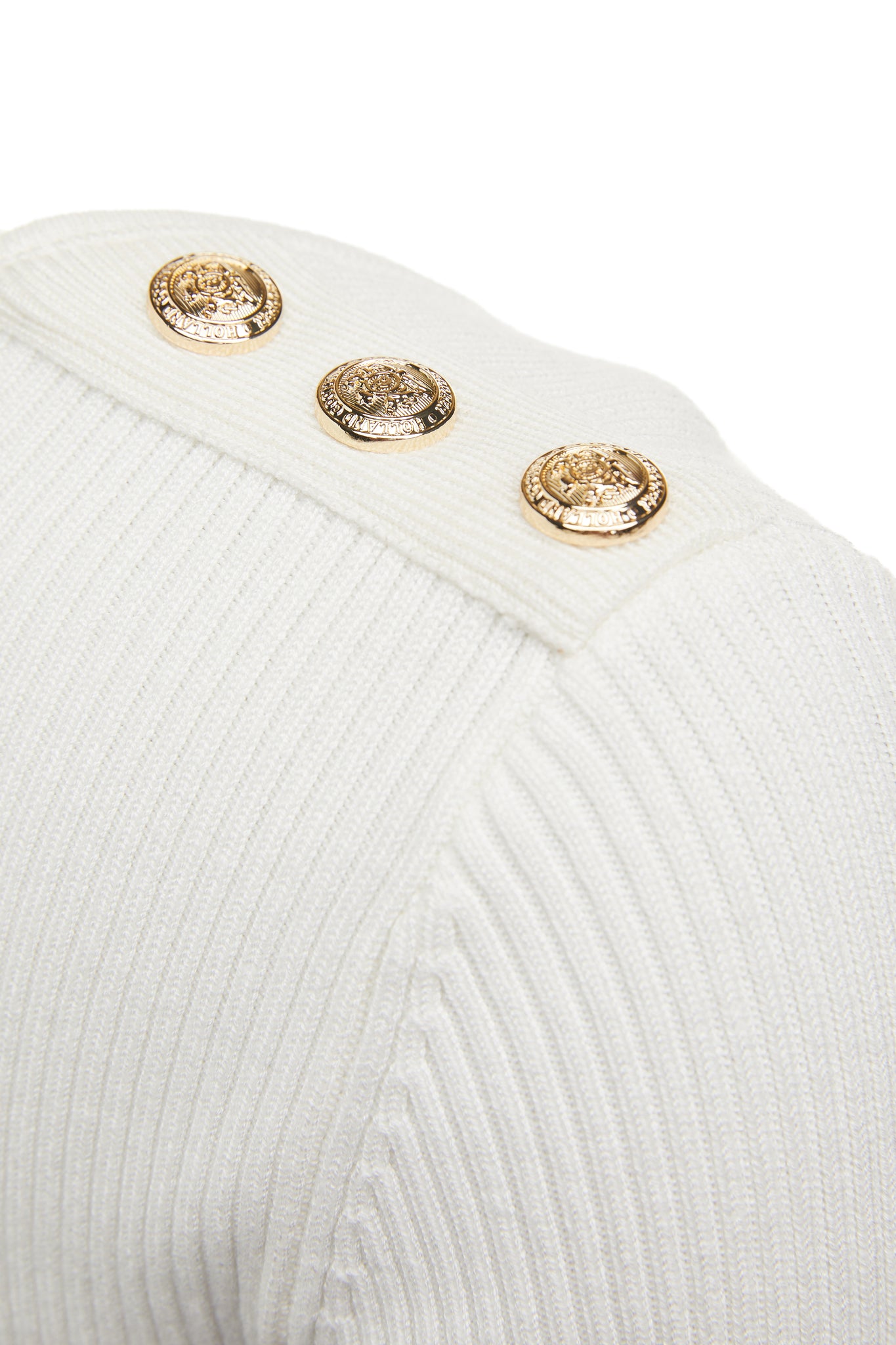 gold button detail accross shoulders of a form fitting finely ribbed long sleeved knitted top in cream with a sweetheart neckline 