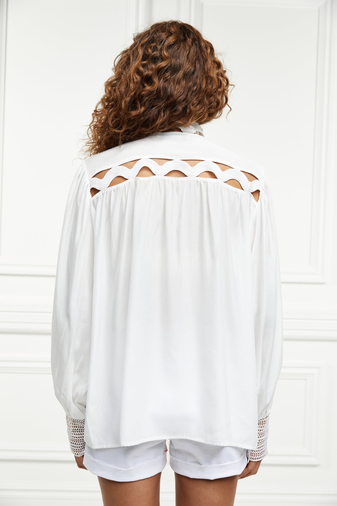 back of womens white polyester shirt with lace detail to the collar shoulders and arm cuffs and balloon sleeve and womens white denim short