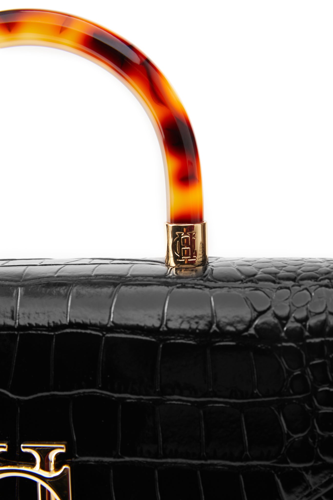close up of gold hardware joining the acetate tortoiseshell top handle to the black croc embossed leather bag