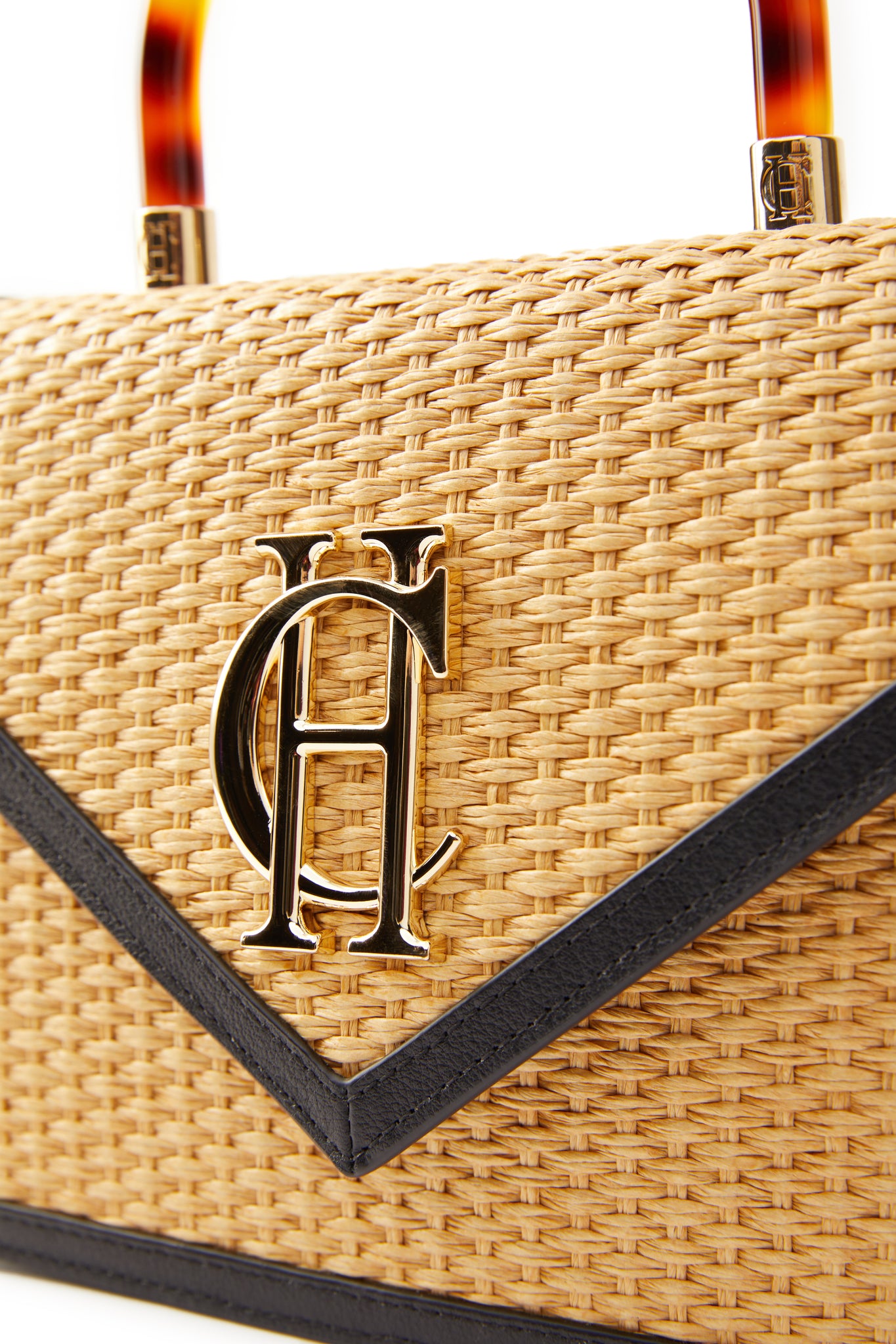 close up of gold hardware on natural raffia bag with acetate tortoiseshell effect top handle