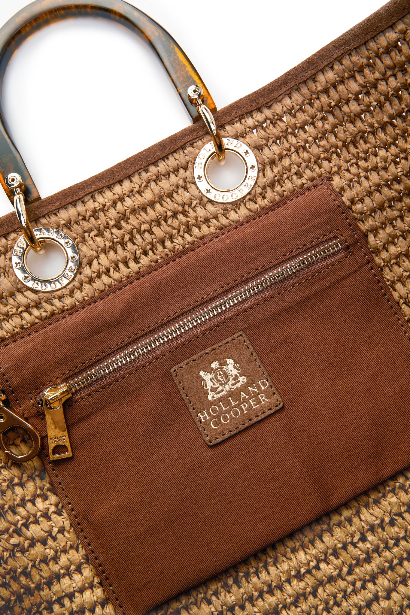 close up of inside tan zip pocket and tortoiseshell handles on natural raffia tote bag
