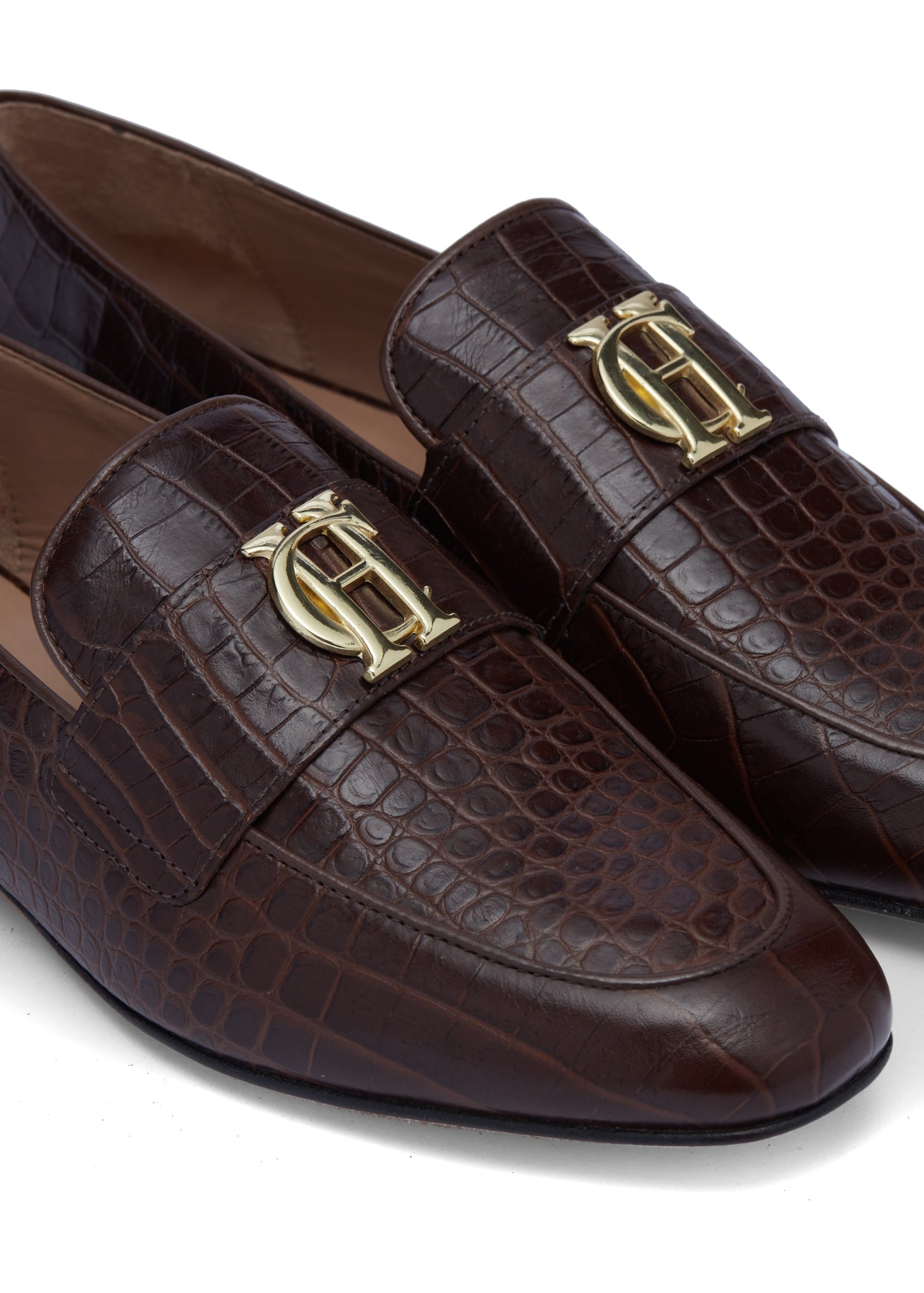 close up of brown croc embossed leather loafers with a slightly pointed toe and gold hardware to the top