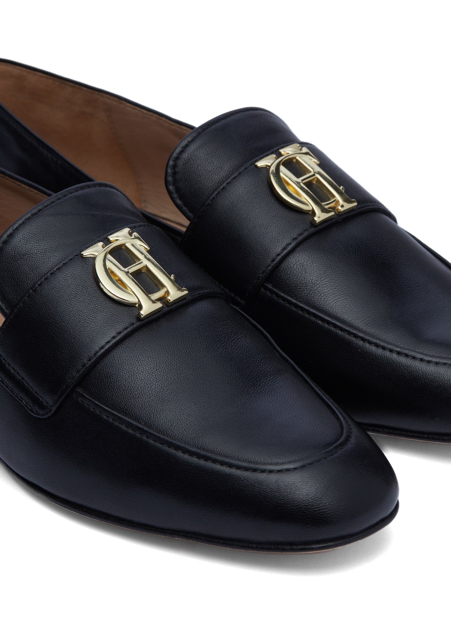 Close up of black leather loafers with a slightly pointed toe and gold hardware to the top