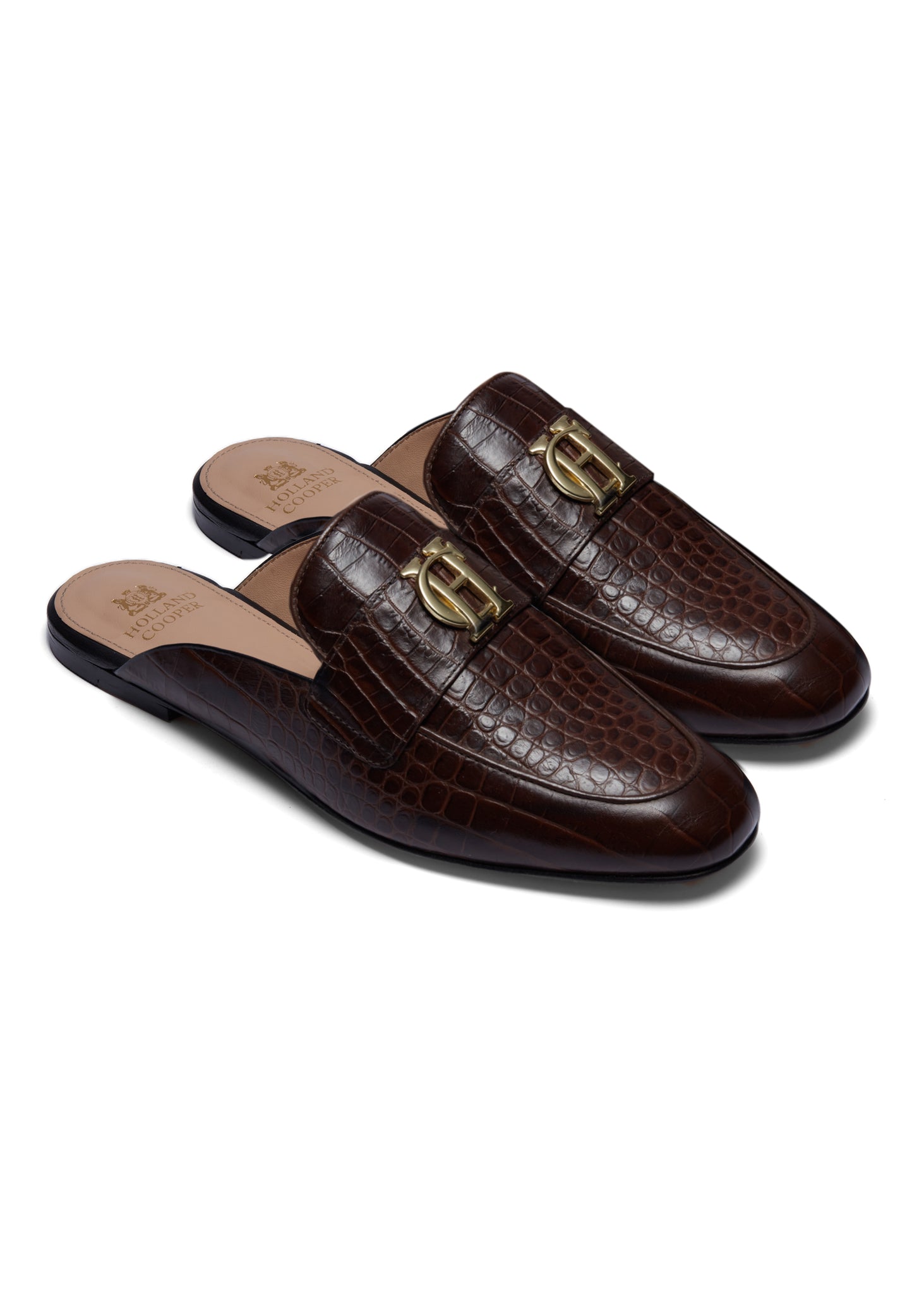 Side view of brown croc embossed leather backless loafers with a slightly pointed toe and gold hardware to the top and gold foil branding on the inner sole