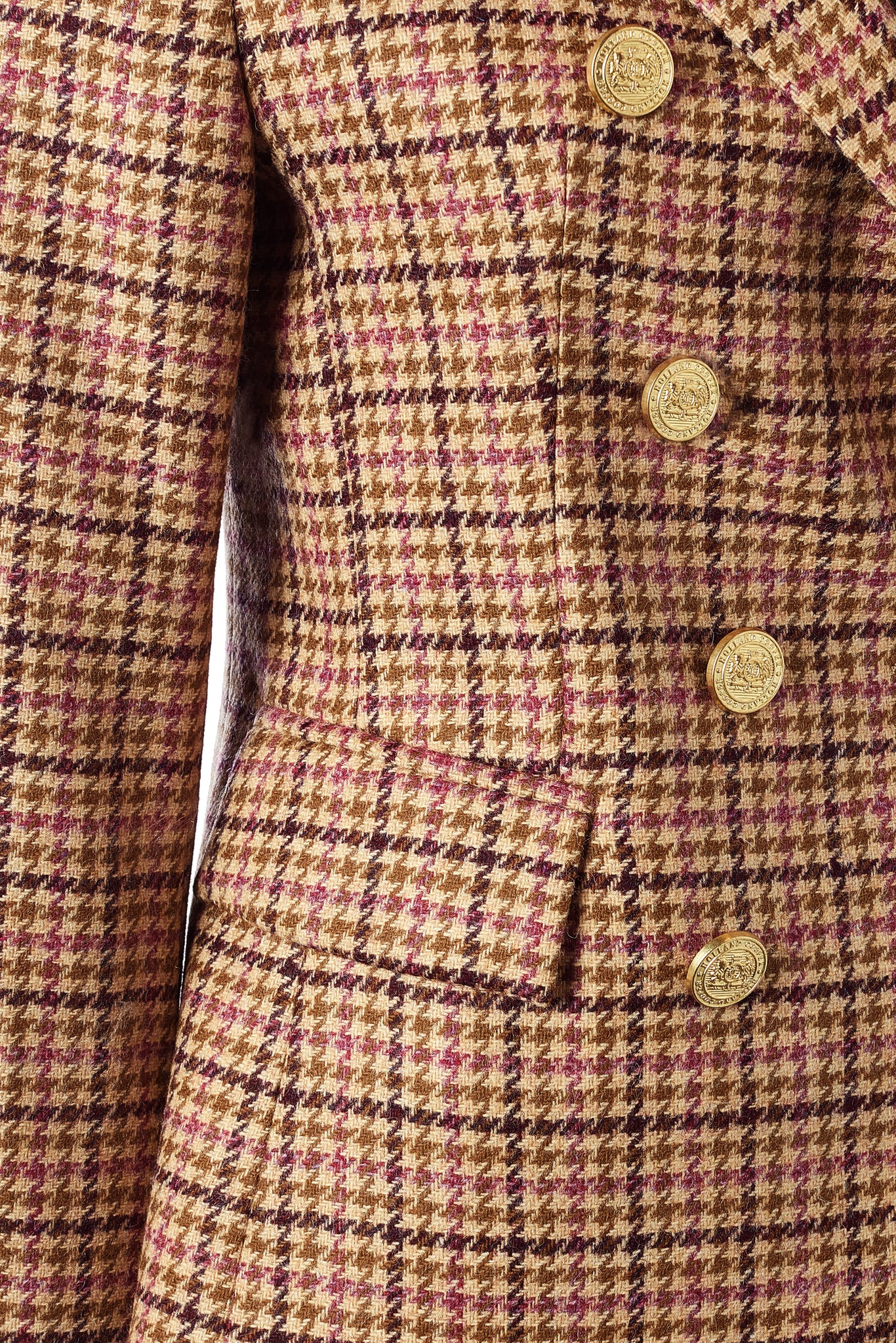 detail of front pockets and gold buttons on British made double breasted blazer that fastens with a single button hole to create a more form fitting silhouette with two pockets and gold button detailing this blazer is made from pink purple and brown check houndstooth fabric