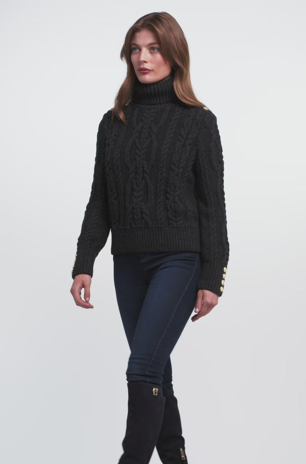 a chunky cable knit roll neck jumper in dark grey with dropped shoulders and thick ribbed cable trims and gold buttons on cuffs and collar