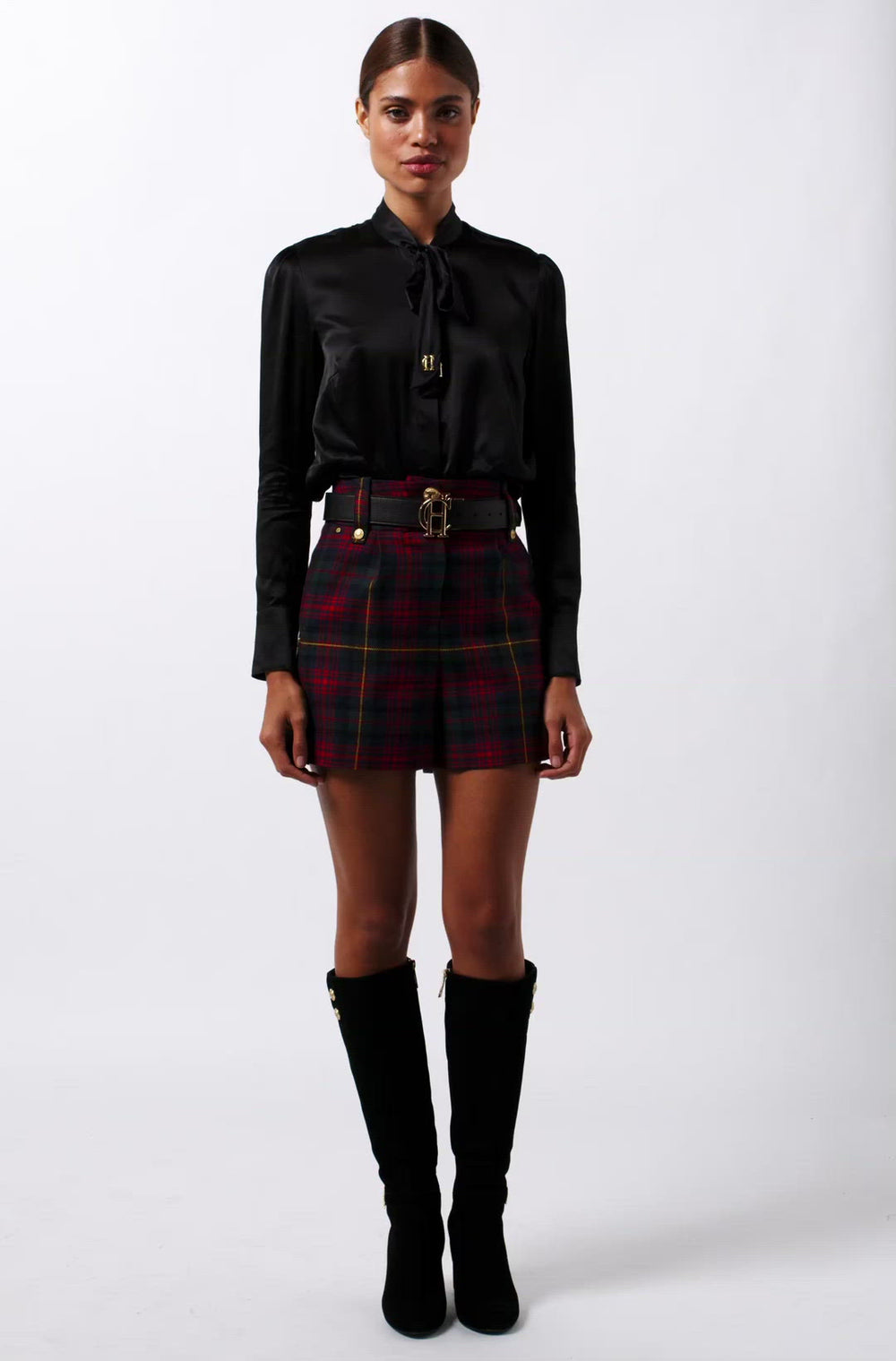 womens red green and blue tartan high rise tailored shorts with two single knife pleats and centre front zip fly fastening with twin branded gold stud buttons and side hip pockets with branded rivet detailing at top and bottom of pockets worn with black silk shirt