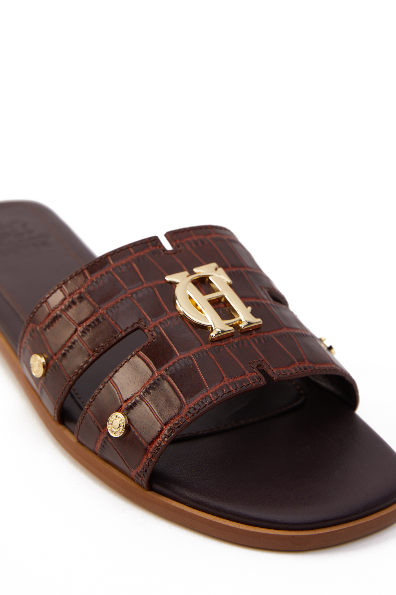 Close up of brown croc embossed leather sliders with a tan leather sole and gold hardware