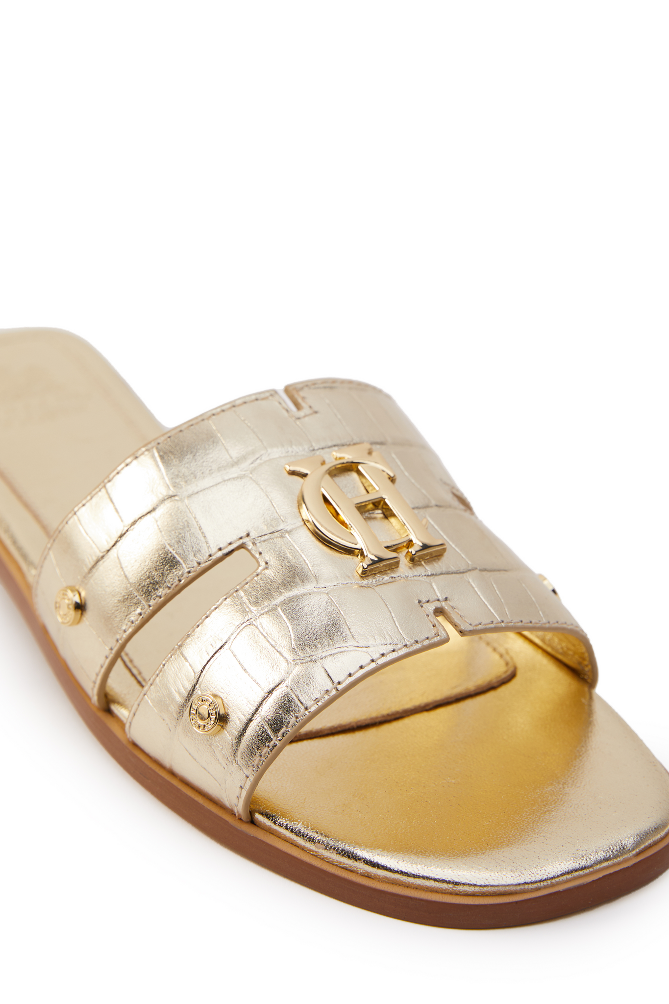 Close up of gold croc embossed leather sliders with a tan leather sole and gold hardware. 