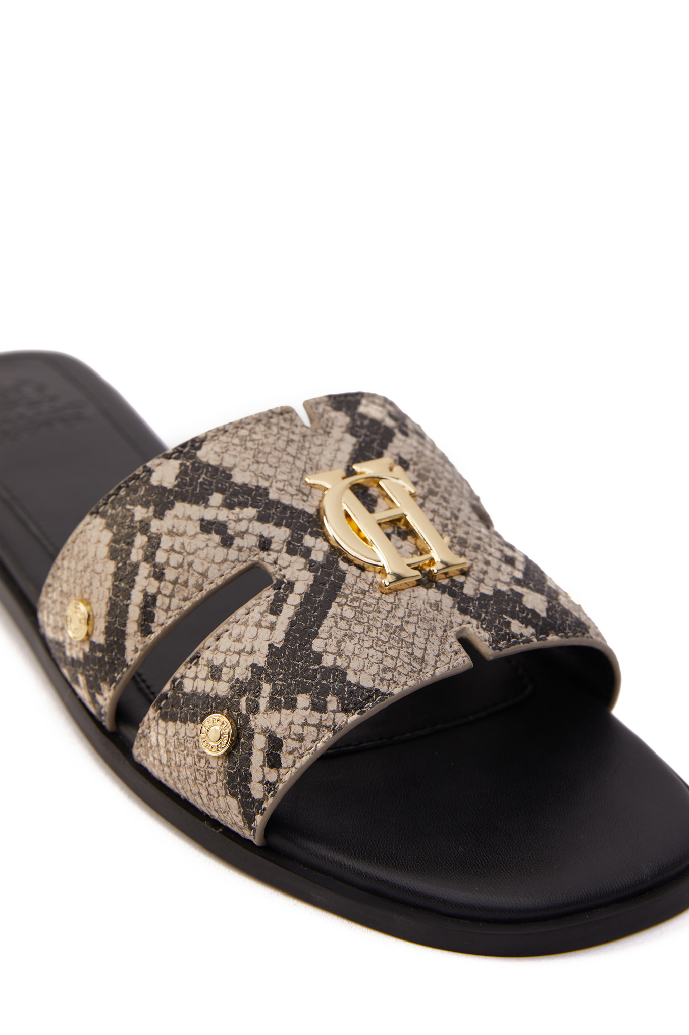 Close up of snake print embossed leather sliders with a black leather sole and gold hardware