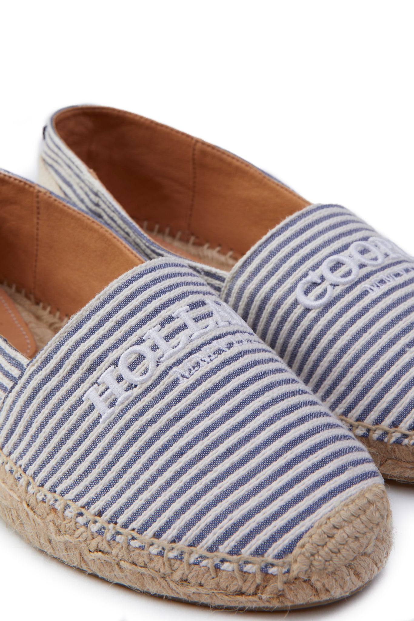close up of classic style white and blue striped canvas espadrille with plaited jute sole and jute toe cap with white embroidered branding on top